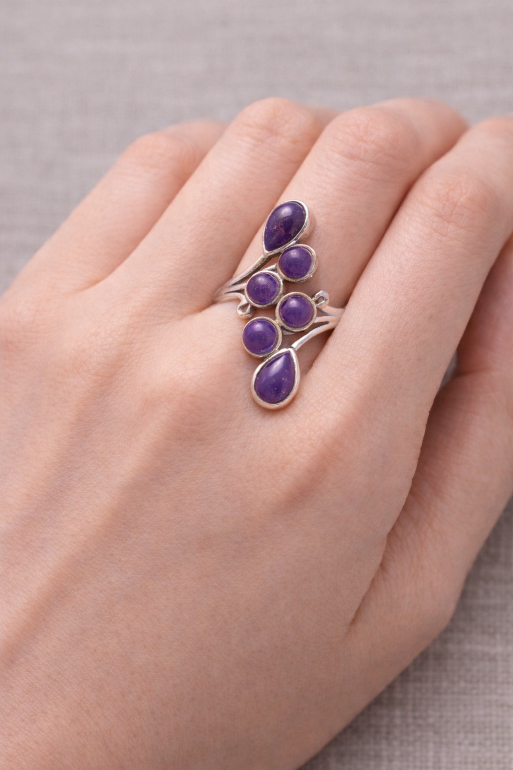 Bague Voile de Sérénité améthyste et argent 925 portée sur le doigt, motifs en argent entourant des pierres d’améthyste violettes.