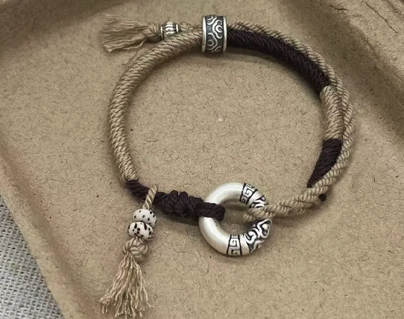 Bracelet Cercle du Bonheur élégant en duo de fils beige et noir, Anneaux en nacre gravés et perles craquelées avec pompon et mousqueton.