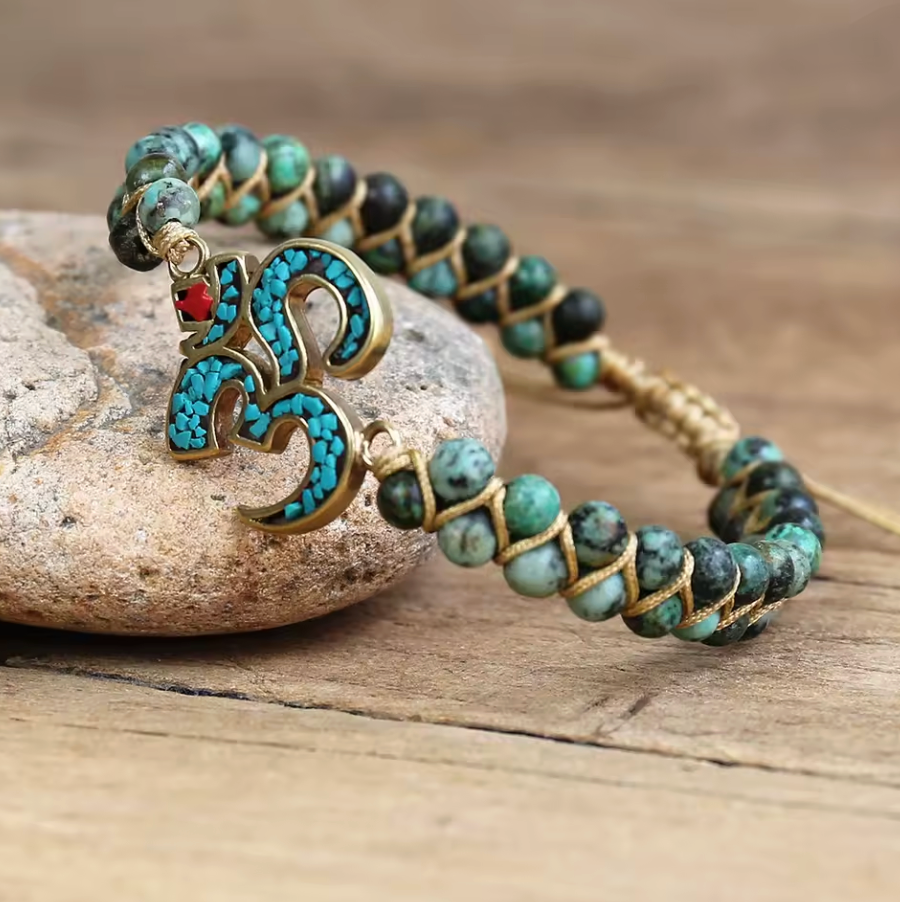 Bracelet coloré avec perles turquoise et nœud doré, motif Om en turquoise et doré, esprit d’Afrique et harmonie spirituelle.
