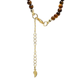 Collier avec pierres œil de tigre et pendentif en forme de lune doré, extension à chaîne pour ajustement et petite feuille au bas.
