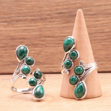 Bague argentée avec malachite verte et motifs en spirale, présentation sur support en bois. Transformation et guérison.