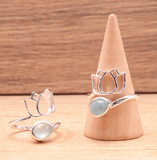 Bague lotus et pierre d’aigue-marine authentique en argent 925, raffinée sur un présentoir en bois.