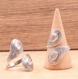 Bague Aura de Tendresse – Quartz Rose & Argent 925: ensemble de bijoux en argent 925 avec pierre d'un quartz rose sur bagues et pendentif sur socle en bois.