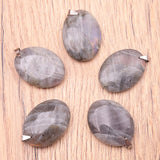 Pendentifs ovale en labradorite violette naturelle assortis, montés en attaches argentées sur bois clair.